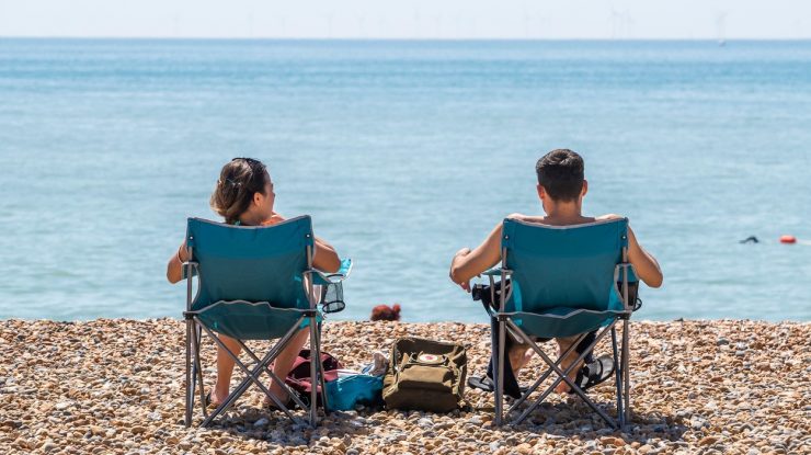 doi tineri stau pe sezlong la plaja