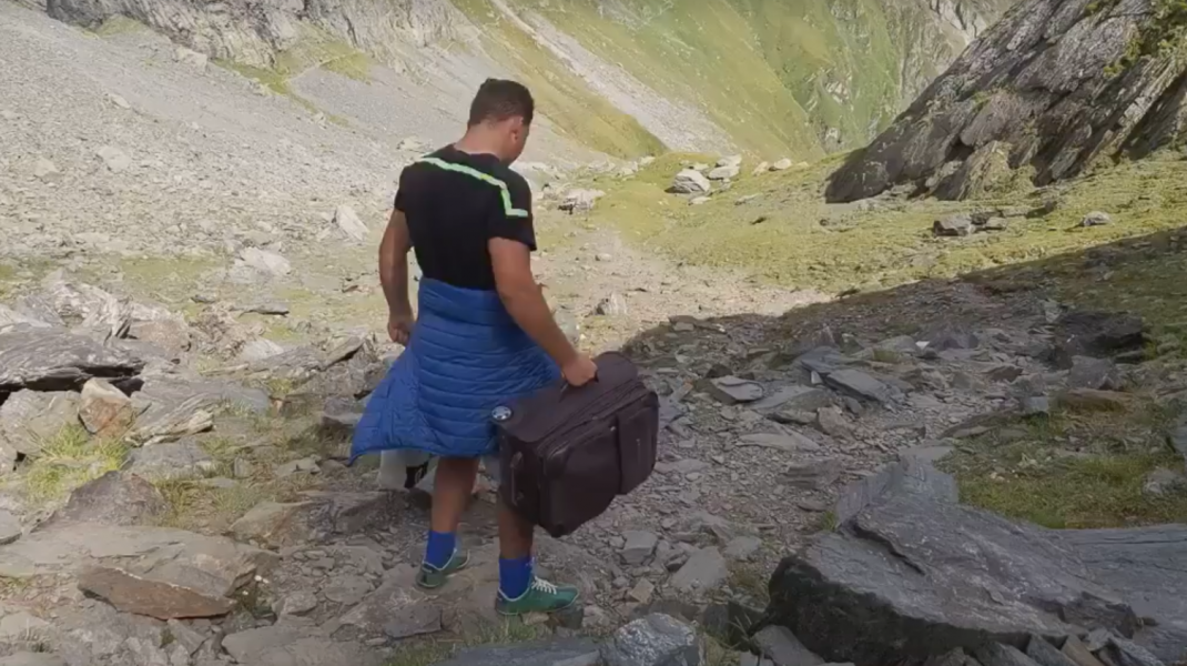 VIDEO Un bărbat merge pe jos, de la Bâlea Lac la Moldoveanu, cu trolerul în mână, acompaniat de o boxă cu muzică populară