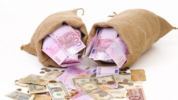 Saci cu bani care se varsă pe o suprafață albă.,