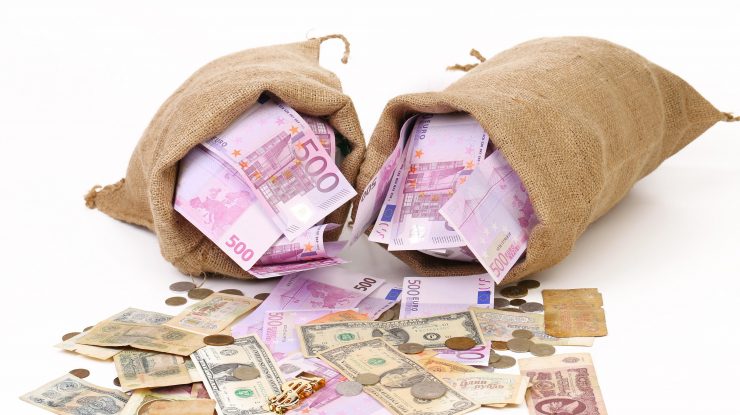 Saci cu bani care se varsă pe o suprafață albă.,