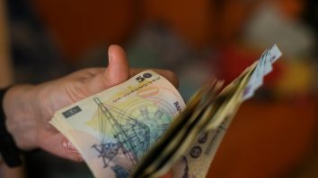 o persoane tine lei romanesti in mana.