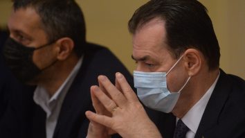 Ludovic Orban poartă mască și ține palmele împreunate în timp ce se uită într-un punct fix.