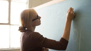 Profesoară care scrie cu creta pe tablă