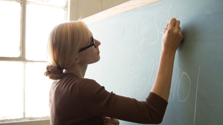 Profesoară care scrie cu creta pe tablă