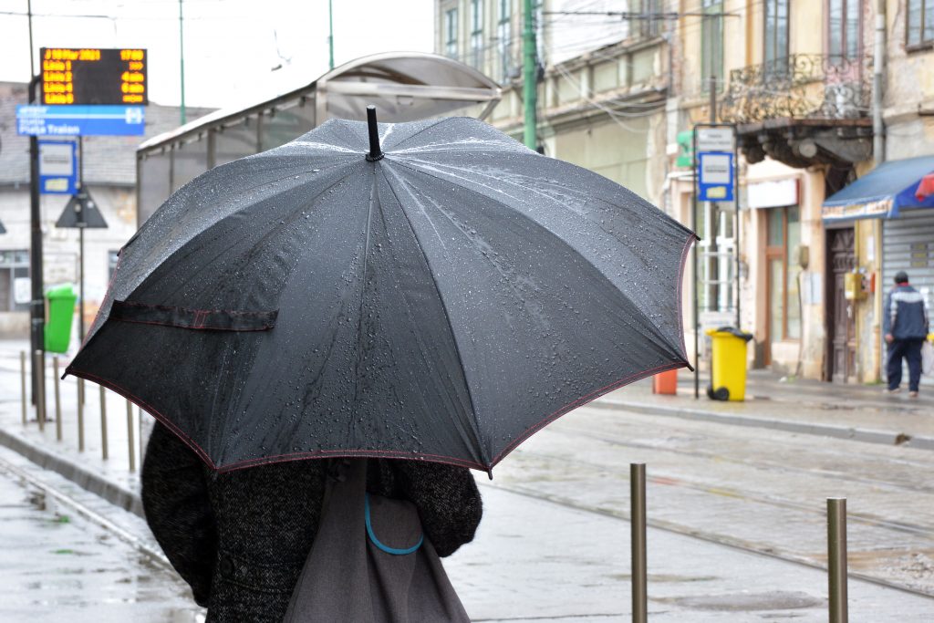 o femeie tine o umbrela in ploaie.