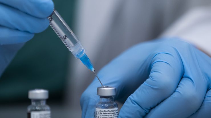 Asistentă care pregătește o doză de vaccin Pfizer.