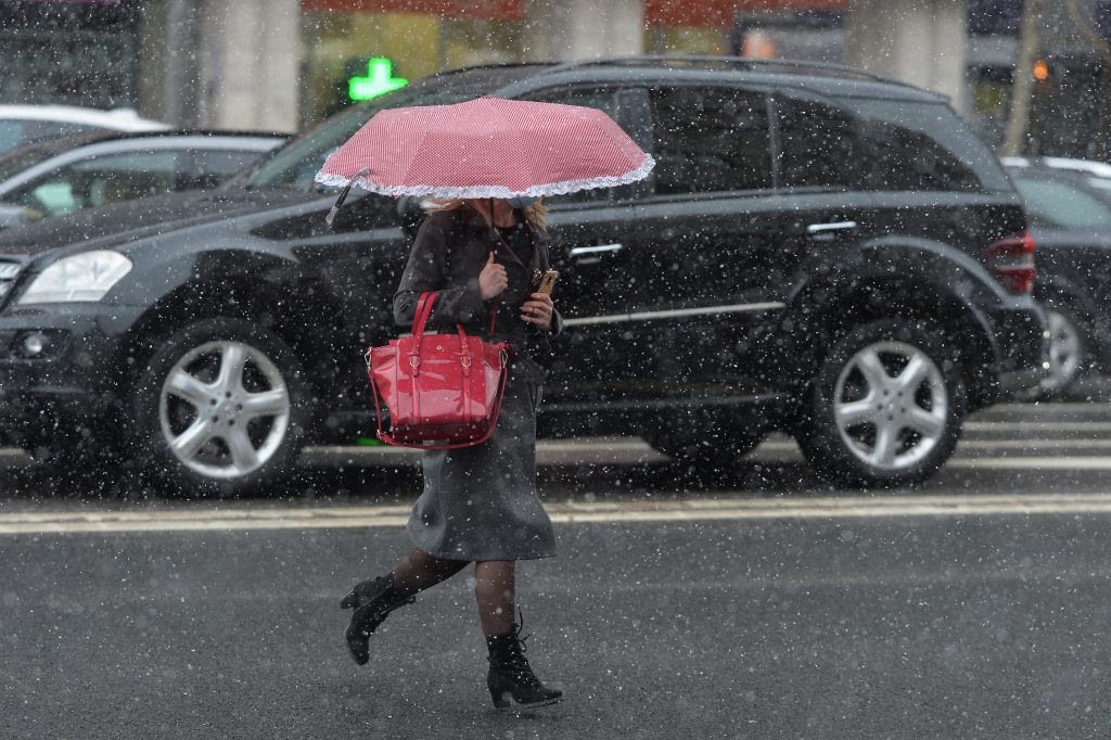 O femeie merge prin ploaie sub umbrelă.
