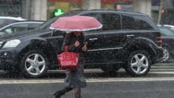 O femeie merge prin ploaie sub umbrelă.