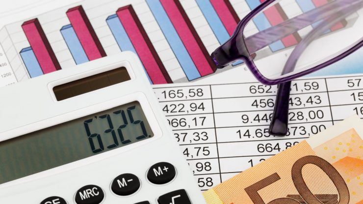 Bani și calculator pe masă.