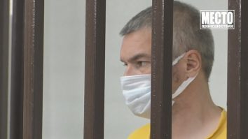 Un bărbat cu masca pe față după gratii