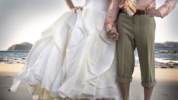 Bărbat și femeie ținându-se de mână. Femeia este îmbrăcată în rochie de mireasă.