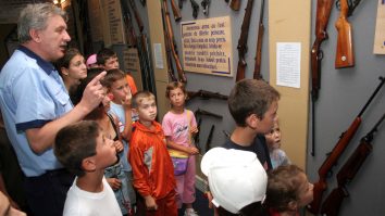 Mai mulți copii privesc la o expziție de arme