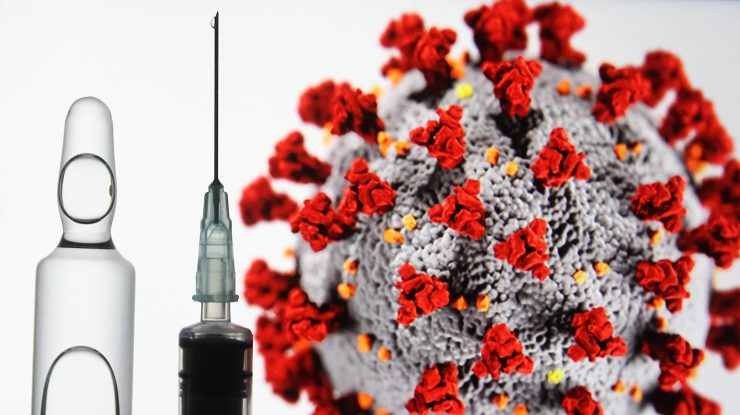 Coronavirusul stă lângă o fiolă de vaccin și lângă o seringă.