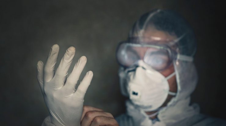 Medic îmbrăcat în echipament de protecție anti-COVID, în întuneric.