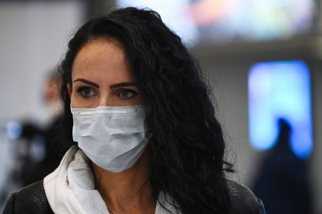 Femeie în aeroport care poartă o mască de protecție împotriva COVID-19.