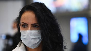 Femeie în aeroport care poartă o mască de protecție împotriva COVID-19.