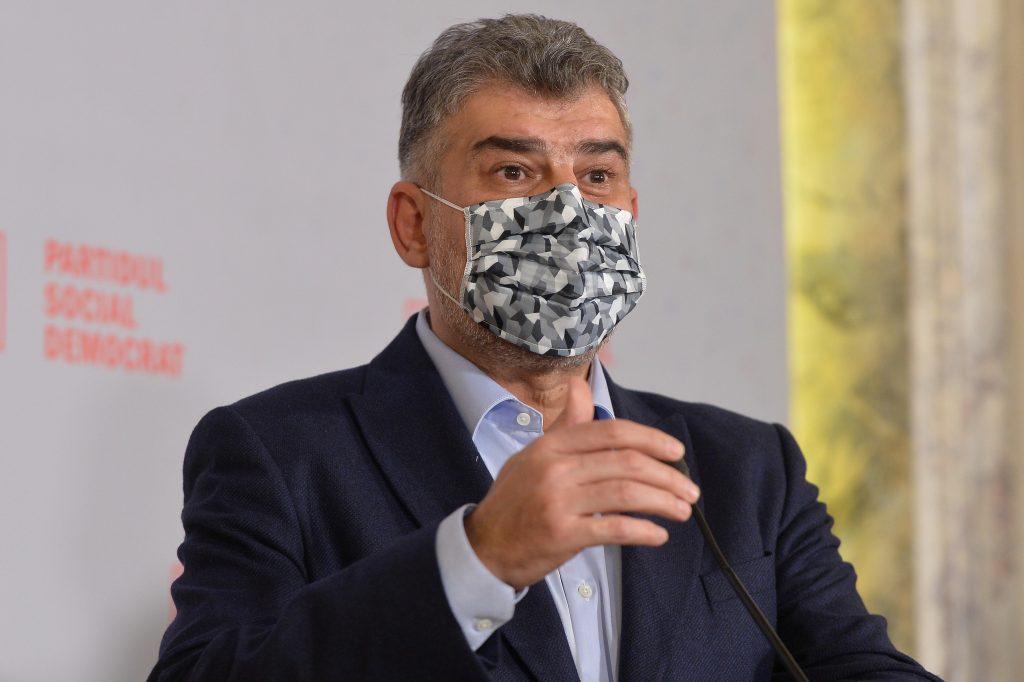 Marcel Ciolacu poartă mască de protecție în timp ce vorbește la microfon.