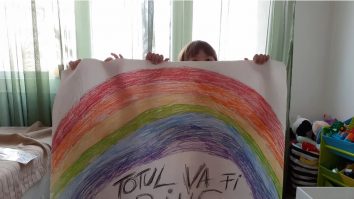Două fetițe arată un curcubeu pe care l-au colorat în timpul pandemiei