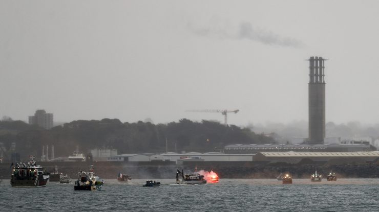 O rachetă de semnalizare este aprinsă în timp ce bărci de pescuit franceze protestează în fața portului Saint Helier, în largul insulei britanice Jersey.