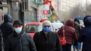 Oameni bătrâni care se plimbă pe străzile din București și poartă mască de protecție.