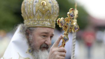 Preto care ține în mână o cruce.