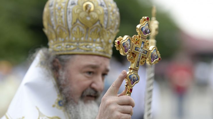 Preto care ține în mână o cruce.