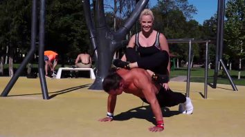 Sportiv care face flotări cu o femeie în spate.