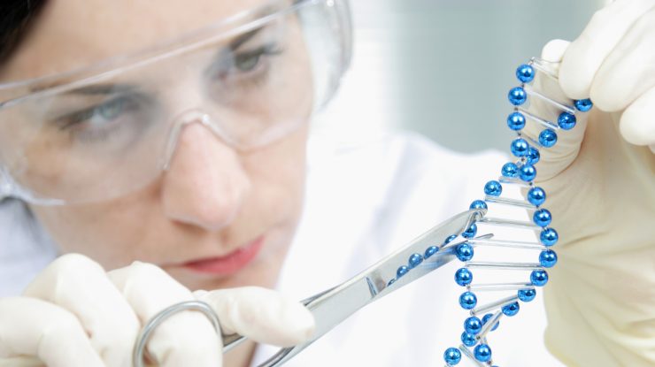 Femeie în laborator care lucrează cu un obiect care întruchipează ADN-ul.