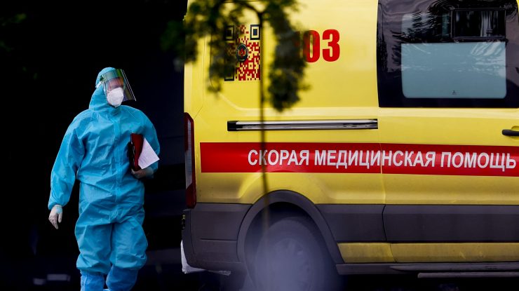 un angajat medical cu costum de protectie langa o ambulanta din rusia, moscova.