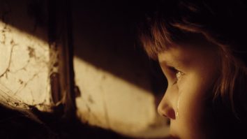 Copil care plânge într-o cameră întunecoasă.