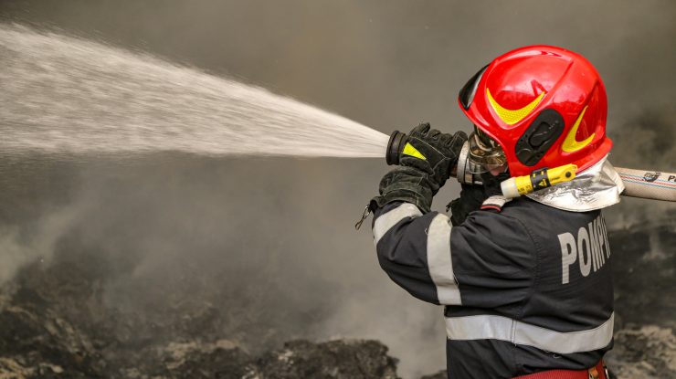 un pompier tine furtunul cu apa la un incendiu.
