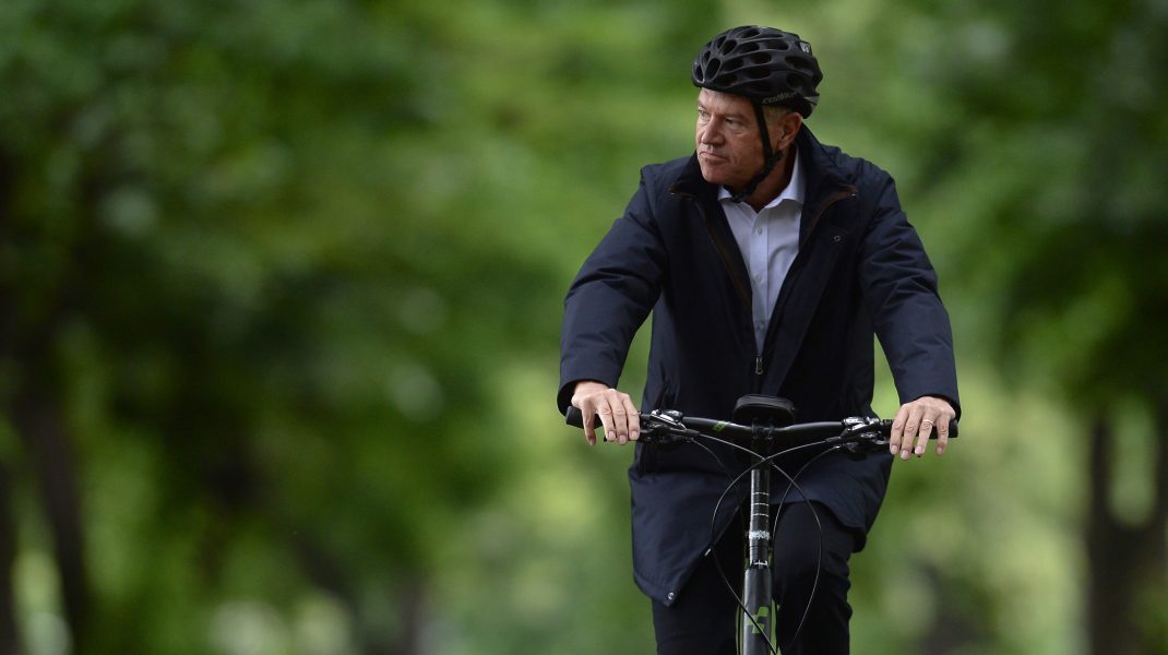 Klaus Iohannis merge pe bicicletă în parc.