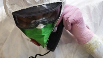 Medic în costum de protecție anti-COVID care vorbește la telefon printr-o mască.