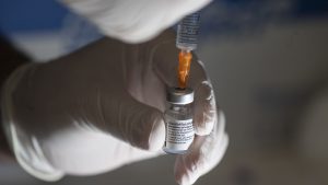 Medic care extrage ser cu o seringă dintr-o doză de vaccin anti-COVID Pfizer.