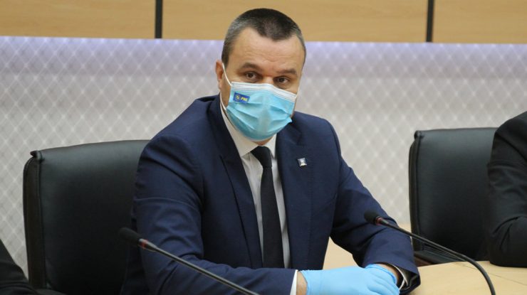 Eugen Pîrvulescu cu masca si manusi la un birou.