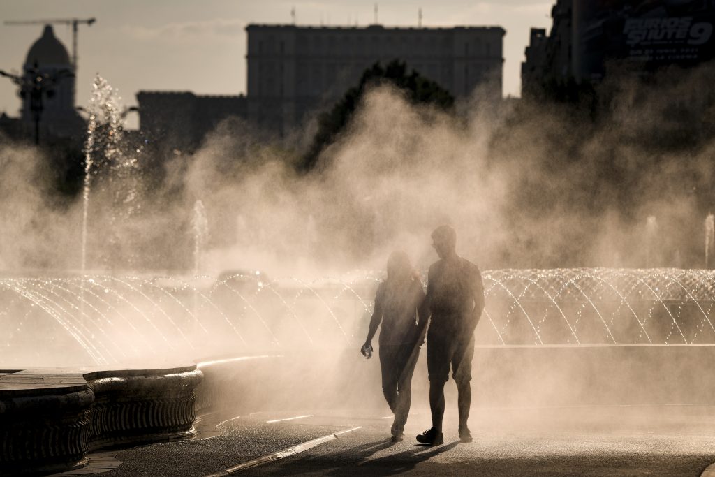 Un cuplu care se plimbă pe lângă o fântână în București, pe vreme de caniculă.