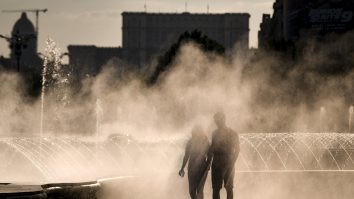 Un cuplu care se plimbă pe lângă o fântână în București, pe vreme de caniculă.