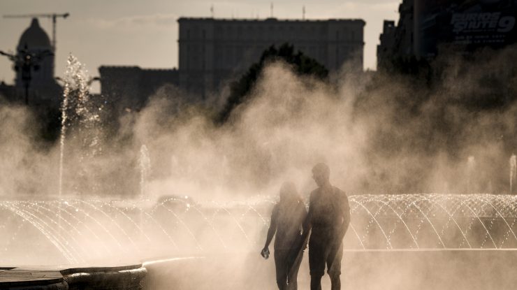 Un cuplu care se plimbă pe lângă o fântână în București, pe vreme de caniculă.