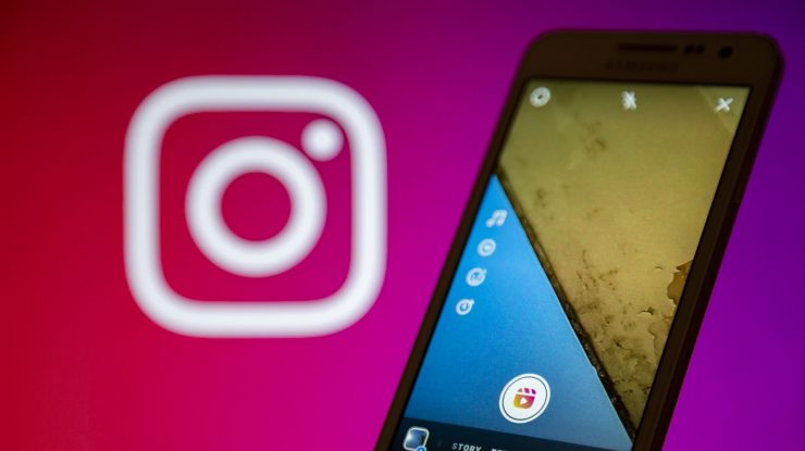 Logo-ul de la Instagram lângă un telefon în care este deschisă aplicația pentru fotografii.