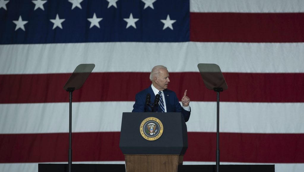 Joe Biden cu drapelul SUA în spate.