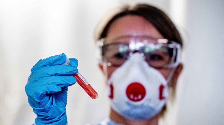 Medic care ține în mână un test de sânge COVID.