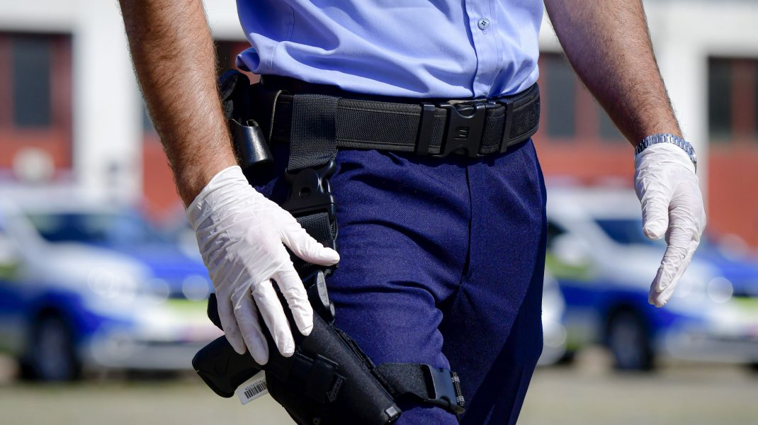 Agent de poliție din România care ține mâna lângă pistol.