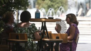 Women sit at a cafe on a hot day in downtown Skopje, North Macedonia, Wednesday July 28, 2021. Authorities in North Macedonia have issued a weather warning and recommended a set of measures on Wednesday as the tiny Balkan country is facing extreme high temperatures rising over 43 Celsius degrees (109 Fahrenheit). (AP Photo/Boris Grdanoski)