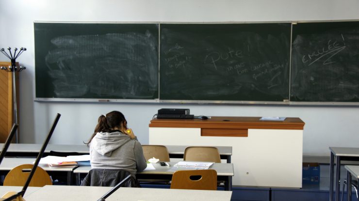 Elev care stă în bancă la școală.