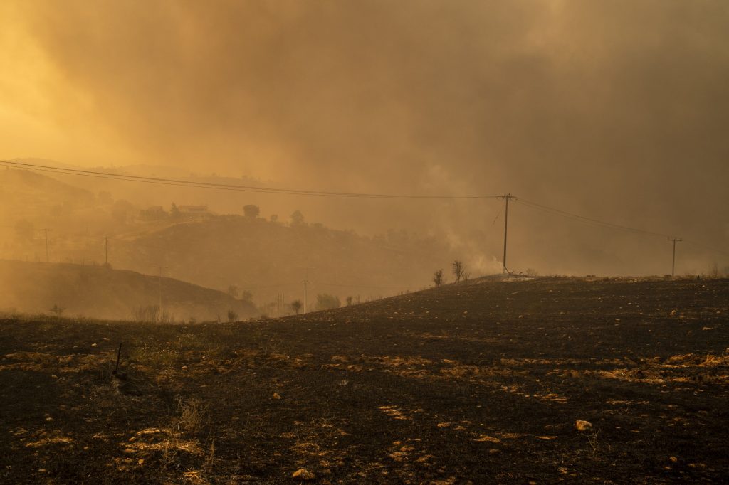 06 august 2021, Grecia, Afidnes: Fumul se ridică din pământul ars într-o zonă împădurită la nord de Atena. Încă de la primele ore ale dimineții, vânturile puternice dinspre vest au continuat să alimenteze numeroasele incendii de vineri. Foto: Al: Angelos Tzortzinis/dpa