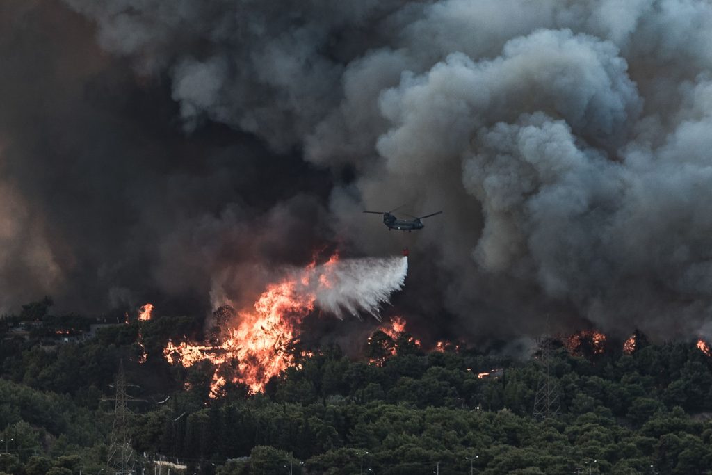 Un avion aruncă apă asupra unui incendiu de vegetație izbucnit într-o zonă forestieră din Tatoi, Grecia. Foto: Hepta