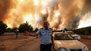 05 august 2021, Grecia, Atena: Un ofițer de poliție lucrează pentru a evacua zona din apropierea unui incendiu de vegetație care arde zona Drossopigi, Varybobi, o suburbie din nord-estul Atenei.