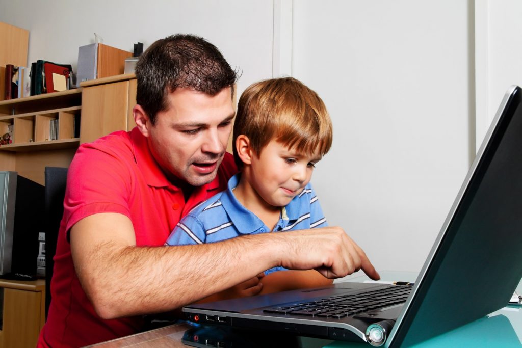 un barbat si un copil se uita la un laptop