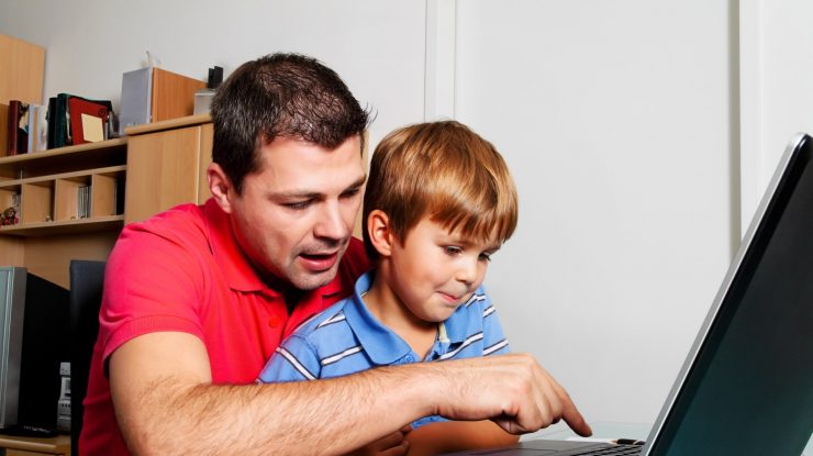 un barbat si un copil se uita la un laptop