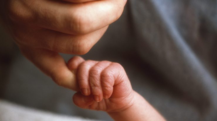 o femeie tine de mana un bebelus